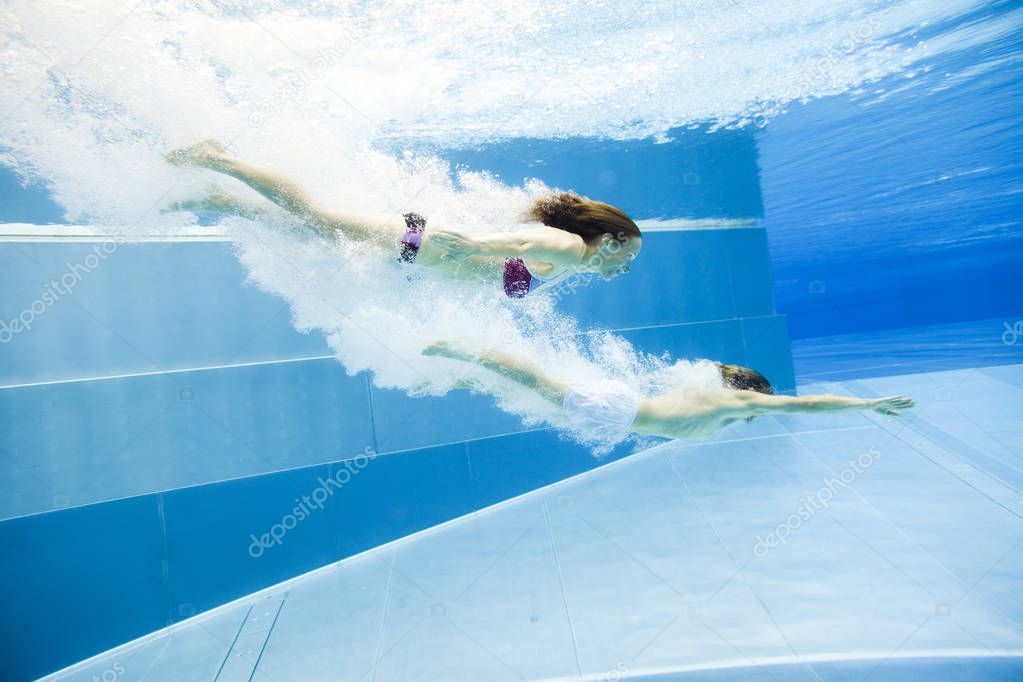 Underwater View Of A Young Couple Jumping Into The Water