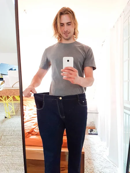 Jovem tomando selfie no espelho mostrando perda de peso — Fotografia de Stock