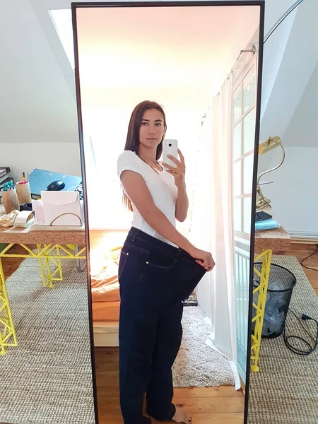 Молода жінка бере Селфі у дзеркалі показує втрату ваги — стокове фото