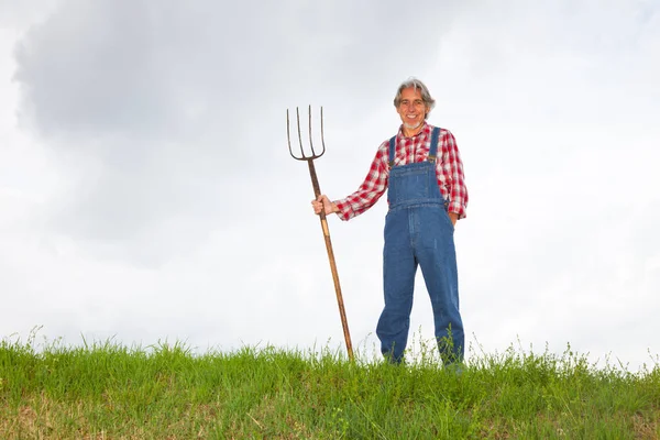Agricultor em pé no topo de uma colina — Fotografia de Stock