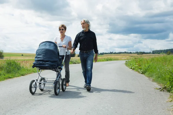 Avós indo para uma caminhada com carrinho de bebê — Fotografia de Stock