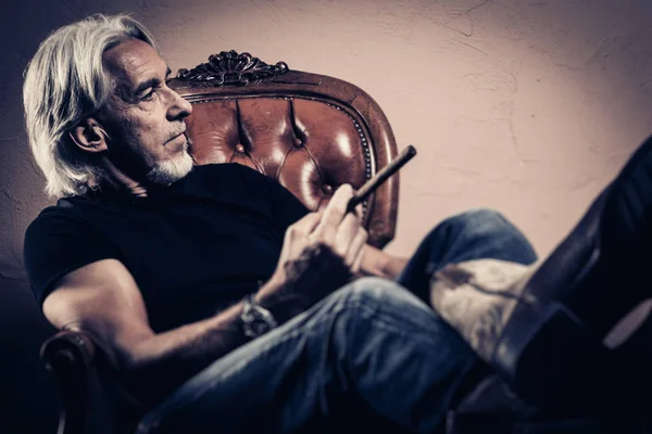 Homme âgé assis dans un fauteuil, portrait en studio — Photo