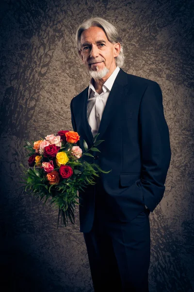Старший мужчина с букетом роз, студийный портрет — стоковое фото
