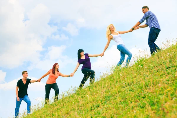 Young People Helping Each Other Climb A Hill — Stock Photo, Image