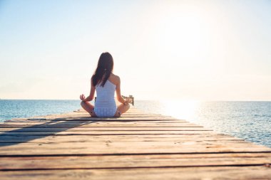 Genç kadın iskelede yoga yaparken