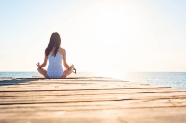 Genç kadın iskelede yoga yaparken