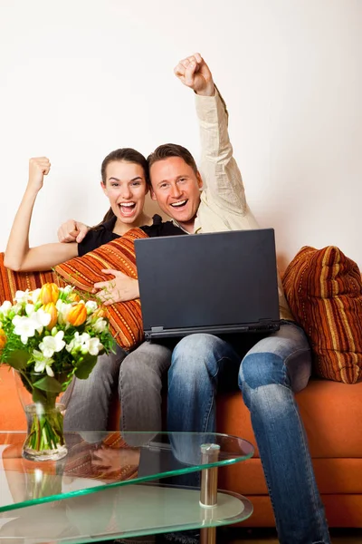 Casal sentado no sofá com um laptop — Fotografia de Stock