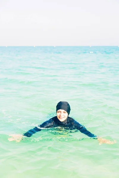Junge Frau im Burkini schwimmt im Meer — Stockfoto