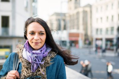 Şehirde yürüyen genç bir kadın.