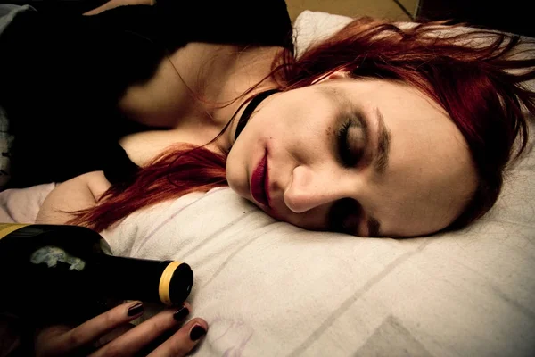 Молодая женщина лежит в постели с бутылкой вина — стоковое фото