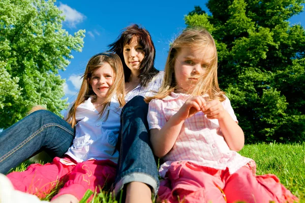 Mère et ses filles assises sur une prairie — Photo
