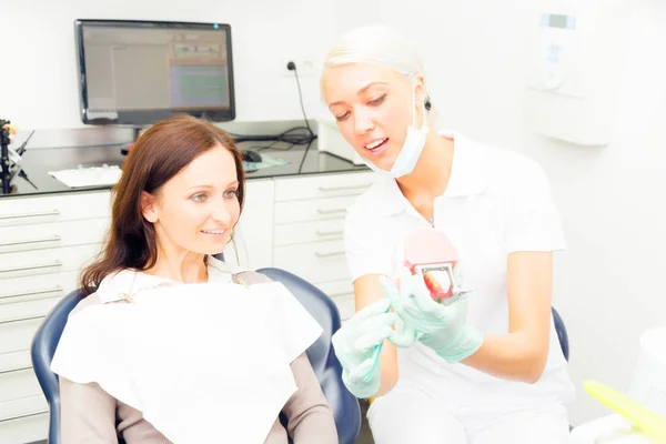 Asistente dental enseñando al paciente a cepillarse correctamente los dientes — Foto de Stock