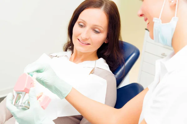 Asistente dental enseñando al paciente a cepillarse correctamente los dientes — Foto de Stock