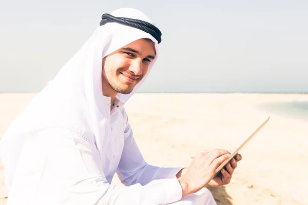 Jovem árabe homem sentado na praia — Fotografia de Stock