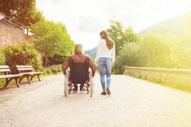 Tekerlekli sandalyede parkta gezen genç bir çift.