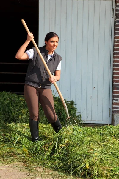Jovem mulher em uma fazenda com feno garfo — Fotografia de Stock