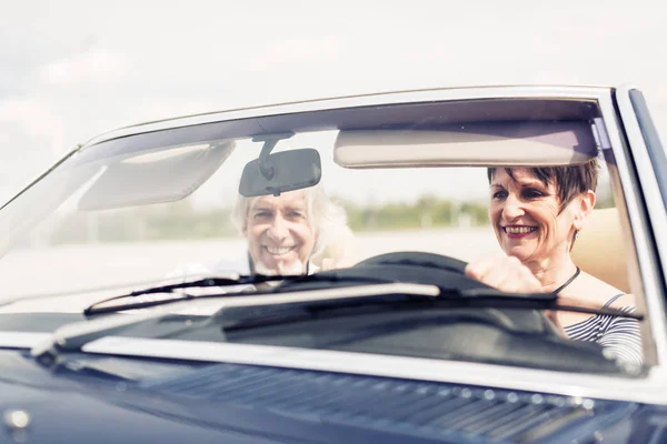 Casal sênior dirigindo um carro clássico conversível — Fotografia de Stock