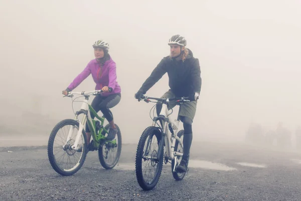 Joven pareja ciclismo a través de la niebla —  Fotos de Stock
