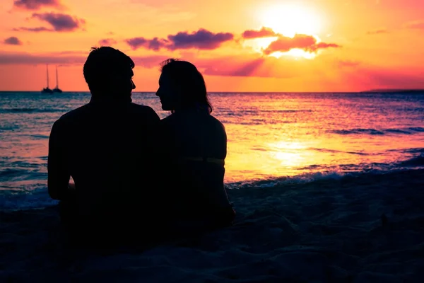 Pareja joven disfrutando de la puesta de sol por la playa — Foto de Stock