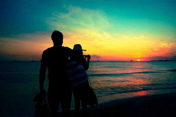 Pareja joven disfrutando de la puesta de sol por la playa — Foto de Stock