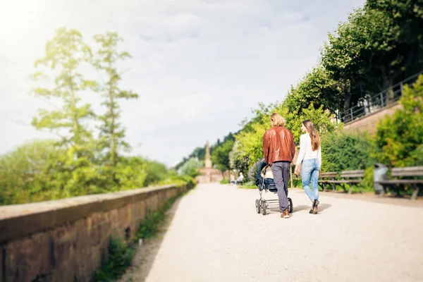 Young Parents With Baby Stroller In The Park — Stock Photo, Image