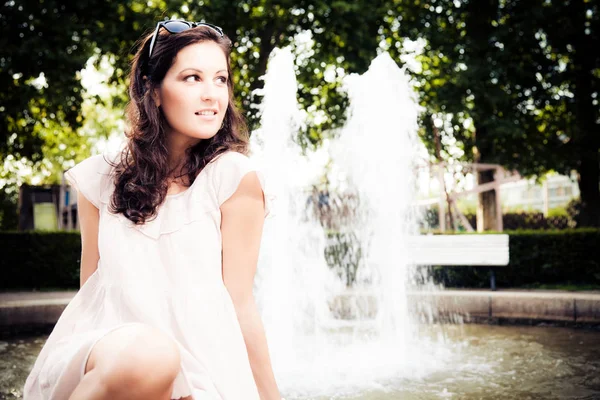 Jeune femme assise près d'une fontaine — Photo