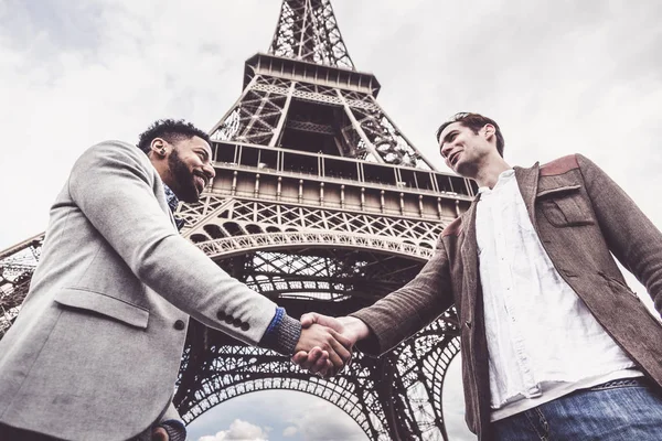 Двое мужчин пожимают руки у Эйфелевой башни — стоковое фото