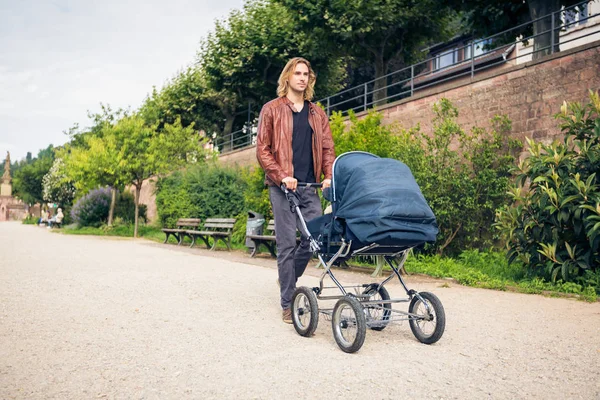 Jonge vader met baby wandelwagen in het park — Stockfoto