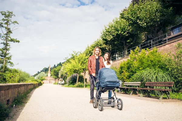 Jonge ouders met Baby wandelwagen In het Park — Stockfoto