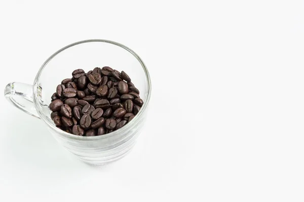 Przezroczyste szkło kubek z ciemne ziarna kawy. — Zdjęcie stockowe