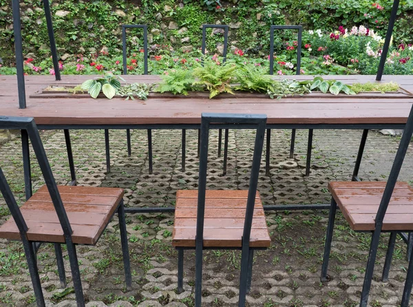 Table à cadre en métal et chari dans le jardin de fleurs . — Photo