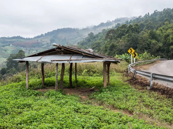 Velho galpão de madeira perto da curva estrada de asfalto . — Fotografia de Stock