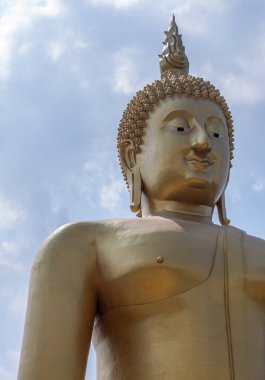 Büyük altın Buda heykelinin ön tarafında gülen yüzlü bir heykel.