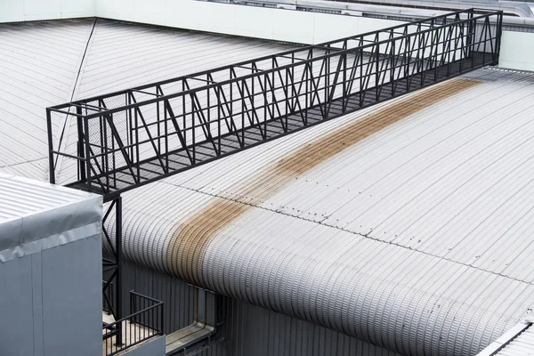 El puente de metal negro está atravesando el techo del almacén.. —  Fotos de Stock