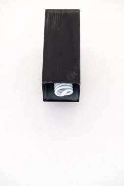 Modern siyah metal çantasındaki küçük floresan ampul modern ofans binasının beyaz beton duvarında.. 