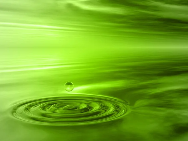 Concept or conceptual green liquid drop falling in water with ripples and waves background