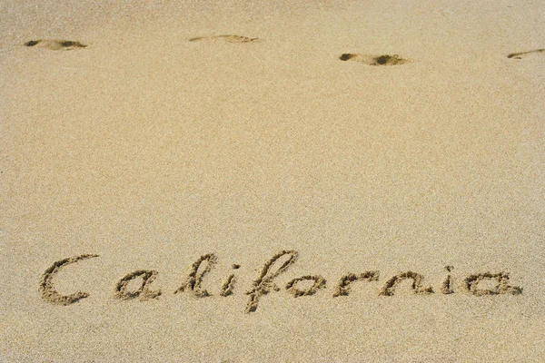 Califórnia manuscrita na areia em uma praia — Fotografia de Stock