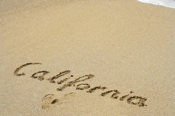 Califórnia manuscrita na areia em uma praia — Fotografia de Stock