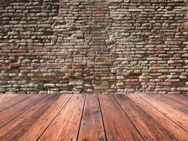 与老式石头或砖的背景墙上的木旧地板 — 图库照片