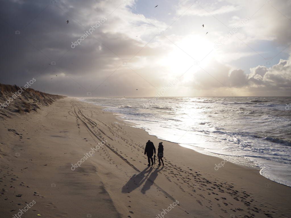 People on a beach walk at sunset