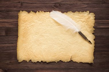 Beyaz tüy ve eski kağıt ahşap yüzey üzerinde