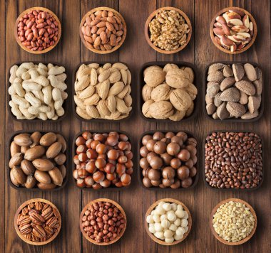 Arka plandaki tahta masada soyulmuş ve kabuklu fındıklar. bileşik sağlıklı besin: ceviz, fındık, ceviz, badem, macadamia, fıstık, çam, Brezilya.