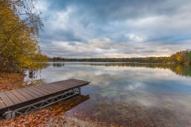 Lakeside iskele, düşmüş yaprakları ve ağaç sınırından parlak Güz