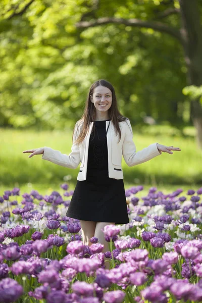 Chica feliz de pie en un campo de tulipanes — Foto de Stock