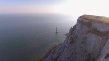 Beyaz tebeşir kayalıklarla ve deniz ile gün batımında güzel fener