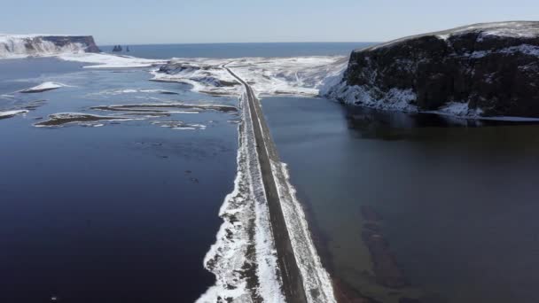 アイスランドの湖を渡る狭い道路に沿って運転する車 — ストック動画