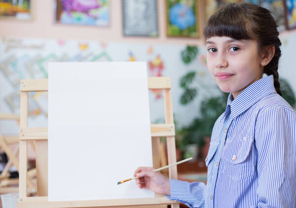 Artistic background  with copy space. Girl at easel with paper and paint brushes.