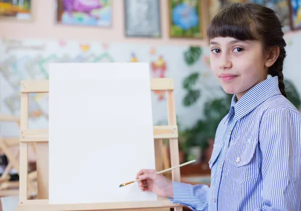 具有复制空间的艺术背景 女孩坐在画架前 手里拿着纸和刷子 图库图片