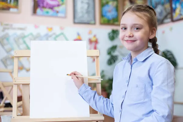 具有复制空间的艺术背景概念 女孩坐在画架前 手里拿着纸和刷子 免版税图库图片