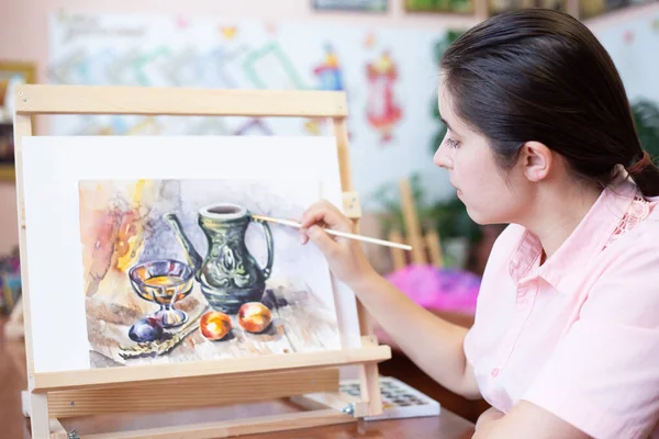 画架上的年轻女艺术家在艺术学校里静坐着 免版税图库照片